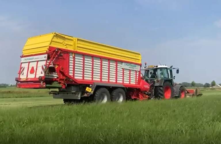 Tractor met kneuzer op het weiland